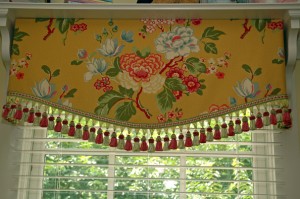 This is a close up view of the soft cornice. The floral motif is centered and the large tassel trim alternates in pink & green.