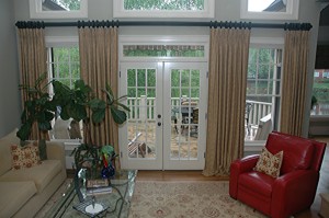One way to unite French doors and side windows is to create the illusion of functional draperies along the "wall space". They are installed on a fluted rod with carved rings from The Finial Company that expands the width of the wall
