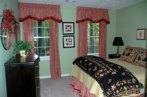 To give the illusion of higher ceilings and larger windows, we mounted these valences almost to the ceiling. They are pencil pleated and lined with red cotton tassel fringe along the serpentine edge. The pleated draperies are lined and interlined. We also fabricated a fully lined bedskirt with an inset banding along the bottom of the skirt for an added detail.