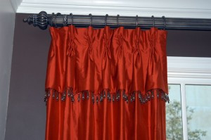 These bright silk draperies are some of my favorite against this dark chocolate wall. The skirted valence shows off the bead wrapped trim from South Africa with the contrast of the silk behind. The hardware has the other detail with the fluted pole, hammered steel rings and the beautifully carved finial.