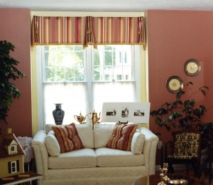 This room had two windows just alike, but the homeowner wanted to keep the light in as much as possible. We chose this stripe fabric and added gold brush fringe to the bottom of the cornice to give it finished edge. Next we added some ascot jabots, a button and a tassel to complete the soft cornice.