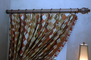 You can see the luxuriousness of the fabric as it is draped assymetrically to one side of the window. The drapery rod is fluted with hammered steel rings from The Finial Company.